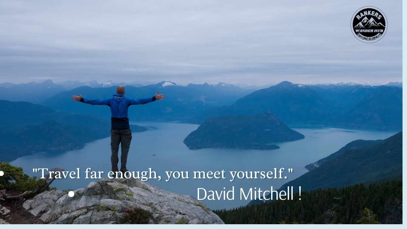 A hiker with arms outstretched overlooking vast mountain lakes.